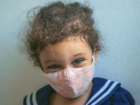 A little girl with a mask with hearts is looking at the cameraの写真素材