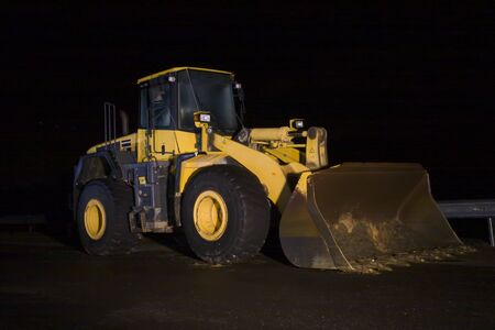 A large yellow bulldozer photographed during a dark night on a construction site.