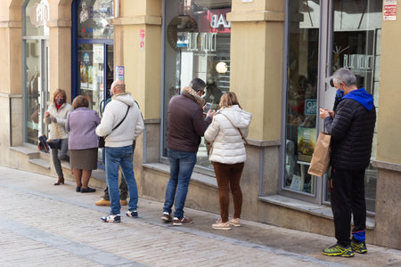 PLASENCIA, SPAIN - DECEMBER 07, 2020: Queue of people waiting to buy Christmas lottery in a lottery...