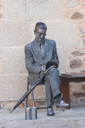 CACERES, SPAIN - April 09, 2011: Living statue for tourist entertainment. An iron man dressed in a classic suit is reading a book and has an umbrella.のeditorial素材