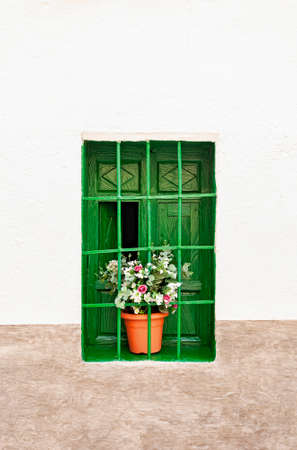 An intense green decorative vintage window with a colorful plastic plant in a pot, plantsの写真素材