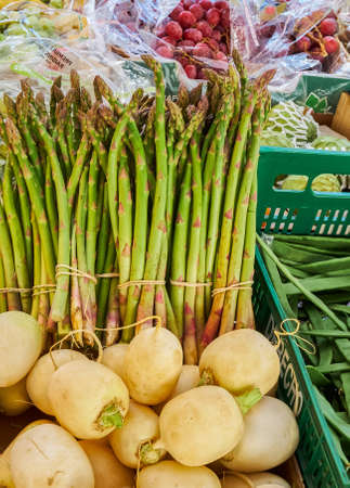 Plasencia, Spain - March 23, 2021: Sale of turnips and asparagus in a street market stall in addition to all kinds of fruitsのeditorial素材