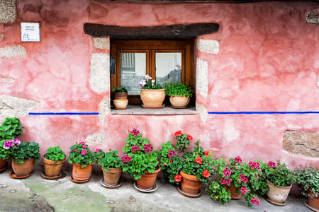 Villanueva de la Vera, Spain - March 08, 2021: A window in the facade of a house with potted plants and drawings of pots on the wall example of the traditional architecture of the townのeditorial素材
