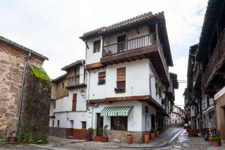 Villanueva de la Vera, Spain - March 08, 2021: A traditional house with wooden beams and balconies next to the church and on the ground floor a grocery store that sells typical homemade sweetsのeditorial素材