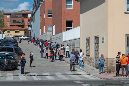 Plasencia, Spain - March 26, 2021: Queue of people with masks and respecting social distance waiting...