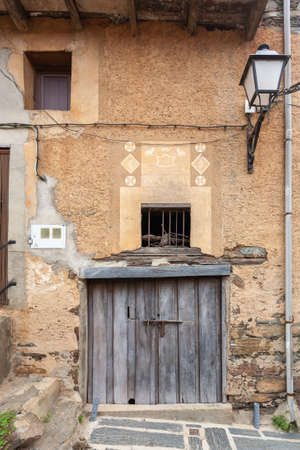 Robledillo de Gata, Spain - March 27, 2021: The door of an old barn for animals and frets in the adobe facade of a traditional style houseのeditorial素材