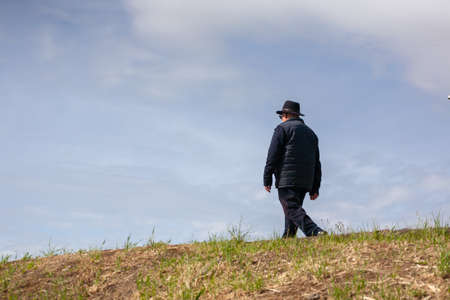 Plasencia, Spain - April 14, 2021: An old man with a hat walks alone in the park to maintain a good physical and mental condition. Low point of view.のeditorial素材