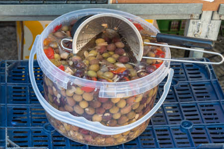 Several different types of olives dressed with herbs. Olives green, black, and green with pepper.