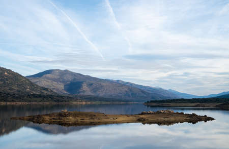 Beautiful landscape with a small island in the center of a lake with calm waters that reflect the background.の写真素材