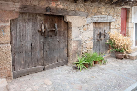 Two old two-leaf wooden doors in stone and adobe constructionsの写真素材