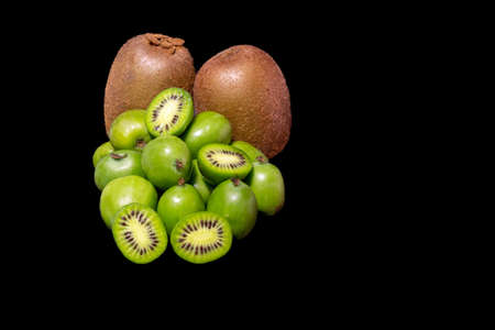 Kiwi fruit close up. Kiwis of different varieties, Green Kiwi and Baby Kiwi on black backgroundの写真素材