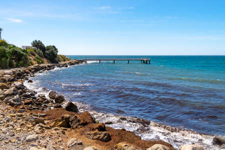 A wooden jetty at the bottom of a stony beachの写真素材