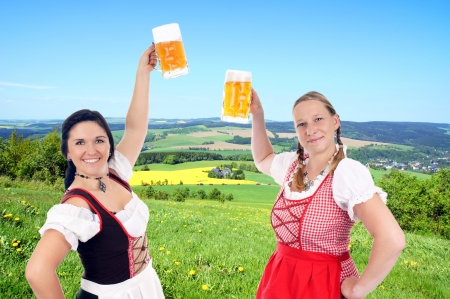 Two young pretty women in dirndl with beer mug in natureの写真素材