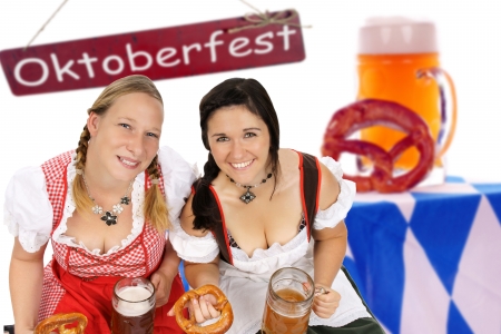 two woman in dirndl with beer mug and pretzel and sign Oktoberfestの写真素材