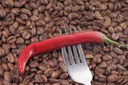 Chili pepper on a fork with coffee beansの写真素材