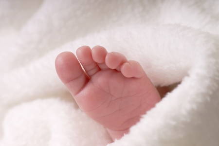 Baby feet look out of a towelの写真素材