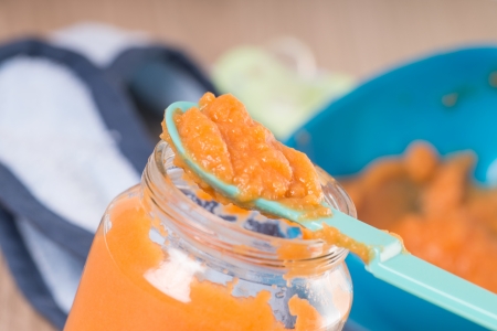 Baby food with porridge bowl and spoon on a wooden backgroundの写真素材