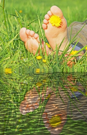 two feet in the grass over reflective waterの写真素材