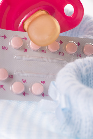 birth control pills with pacifier and baby shoesの写真素材