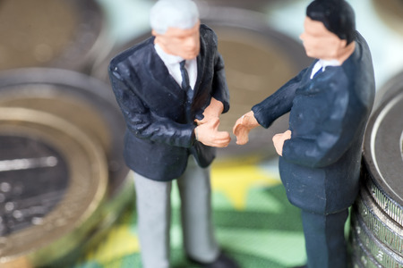 two businessmen with euro coins and euro banknotesの写真素材