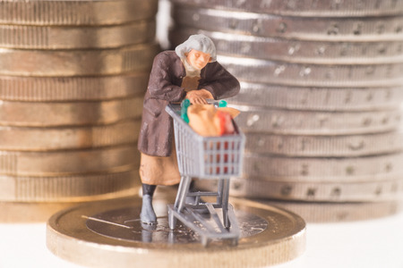 Old woman with shopping cart on a euro coinの写真素材