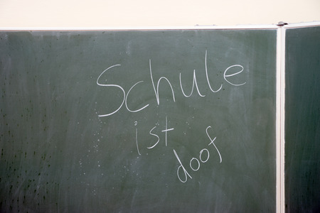 Chalkboard in a classroom with the german words School is stupidの写真素材