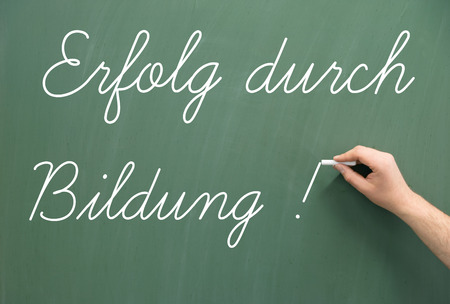 Chalkboard with the german words Success through Educationの写真素材