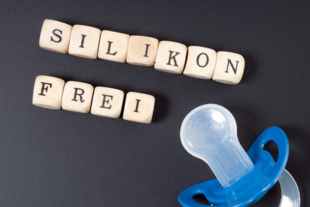 Pacifier and Wooden dice with the word silicone freeの写真素材