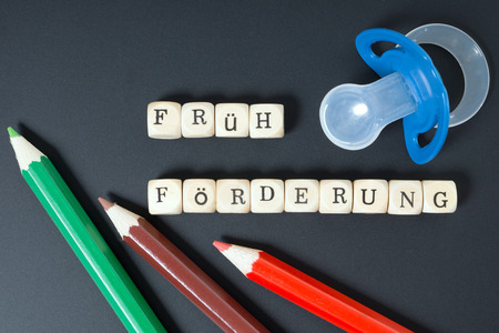 pacifier and Chalkboard with the german words early supportの写真素材