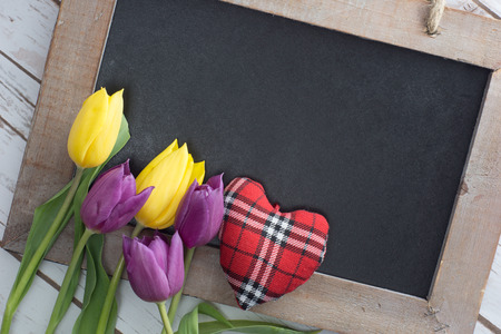 empty blackboard with wooden frame with tulips and little heartの写真素材