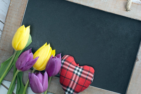 empty blackboard with wooden frame with tulips and little heartの写真素材