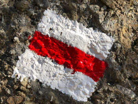 Red and white sign painted on rock marking hiking trail or the Swiss mountain trail markingの写真素材