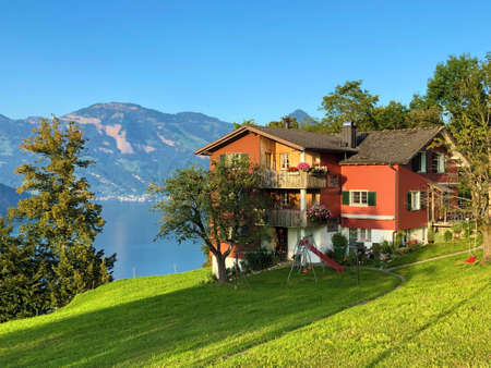 Traditional architecture and farmhouses on the slopes of the Swiss Alps by the lake Lucerne or Vierwaldstaetersee lake (Vierwaldstattersee or VierwaldsÃ¤ttersee) and under the Buochserhorn mountainの写真素材