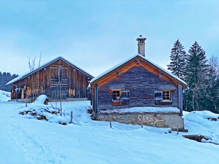 Idyllic Swiss alpine mountain huts dressed in winter clothes and in a fresh snow cover on slopes on...