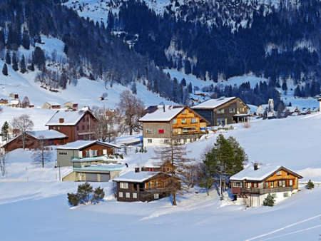 Idyllic Swiss alpine mountain huts and traditional Swiss rural architecture dressed in winter clothes and in a fresh snow cover in the Obertoggenburg region, Wildhaus - Switzerland (Schweiz)の写真素材