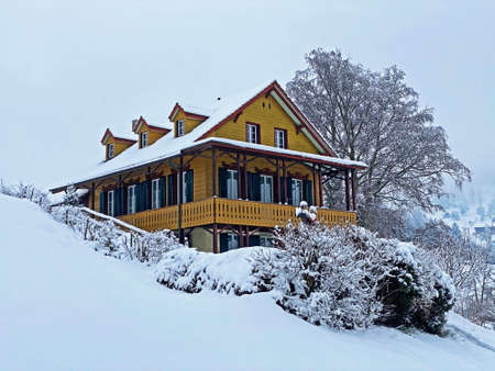 Idyllic Swiss alpine mountain huts and traditional Swiss rural architecture dressed in winter clothes and in a fresh snow cover on the slopes of Mountain Rigi, Weggis - Canton of Lucerne, Switzerlandの写真素材