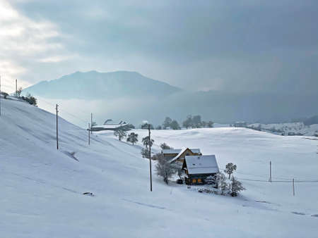 Idyllic Swiss alpine mountain huts and traditional Swiss rural architecture dressed in winter clothes and in a fresh snow cover on the slopes of Mountain Rigi, Weggis - Canton of Lucerne, Switzerlandの写真素材