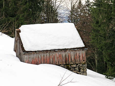 Idyllic old traditional Swiss mountain huts in a fresh snow cover over the Lake Walen or Lake Walenstadt (Walensee), Amden - Canton of St. Gallen, Switzerland (Schweiz)の写真素材
