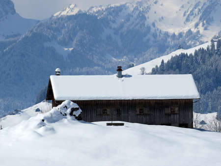 Indigenous alpine huts and wooden cattle stables on Swiss pastures covered with fresh white snow...