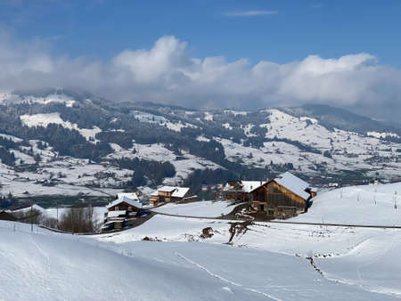 Indigenous alpine huts and wooden cattle stables on Swiss pastures covered with fresh white snow...