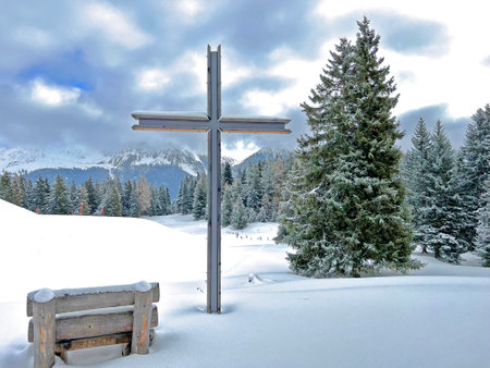 Christian crucifix in the magical winter setting of the Swiss Alps and on the snow-covered alpine pastures of the agricultural-tourist settlement Amden - Switzerland / Schweizの写真素材
