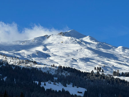 The last rays of the late afternoon sun on the alpine winter snowy peaks above the tourist resorts of Valbella and Lenzerheide in the Swiss Alps - Canton of Grisons, Switzerlandの写真素材