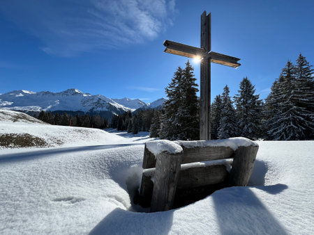 Christian crucifix in the magical winter setting of the Swiss Alps and on the snow-covered alpine pastures the tourist resorts of Valbella and Lenzerheide - Canton of Grisonsの写真素材