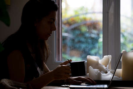 woman working at home while having tea or coffeeの写真素材