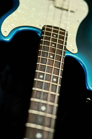Blue and ivory guitar with neck and body exposed on a black background.  Focus on the strings and fret board.の写真素材