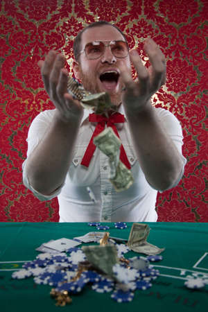 A man wearing glasses, a white shirt, and a red Texas tie sits at a blackjack table  He smiles hugely as tosses his winnings in the air のeditorial素材