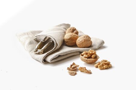 group of cracked walnuts on a kitchen cloth on a white backdropの写真素材