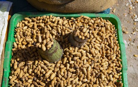 metal scooper in a pile of raw peanuts on a market in Asia