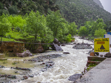 Ourika Valley, Marroco - April 04,2010:wooden bridge over the Ourika valley with a metal sign to a restaurantのeditorial素材