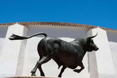 Sculpture of a bull in front of an arenaの写真素材